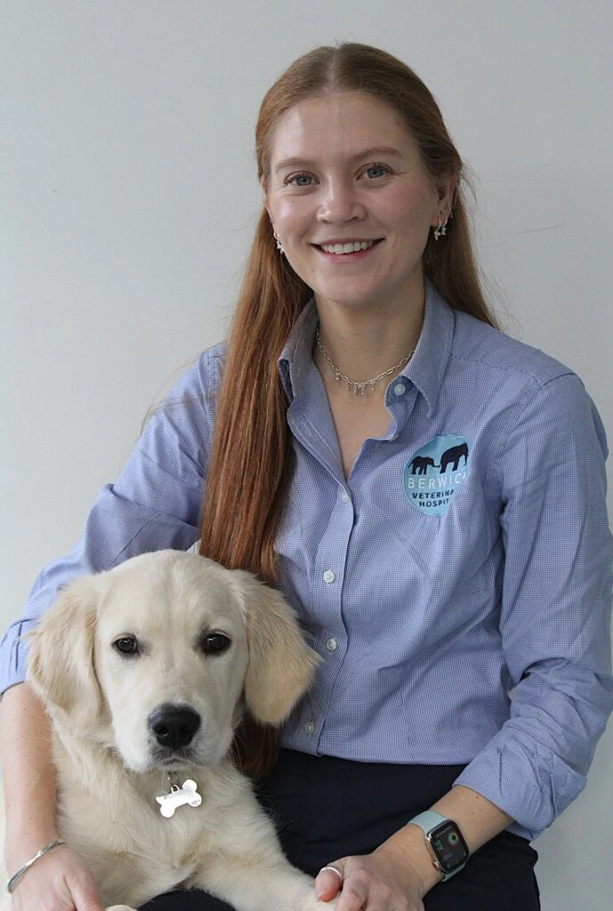 Dr Isabelle veterinarian at Berwick Veterinary Hospital smiling while sitting with a golden retriever dog