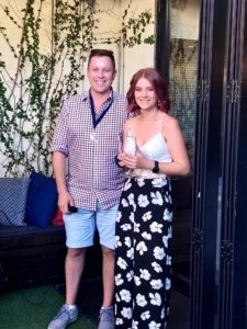 Izzy standing with a man at the BVH Christmas Party and Awards Night 2020, both dressed for the event and holding drinks beside a doorway