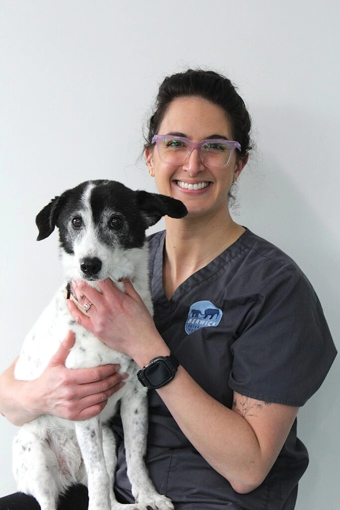Saraid vet nurse at Berwick Veterinary Hospital smiling while holding a black and white dog