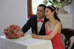 Tracy and Nico sitting together at a table during their wedding celebration with a bouquet of flowers nearby